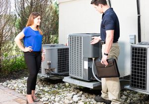 Technician Discussing AC Unit with Homeowner Outside a Building